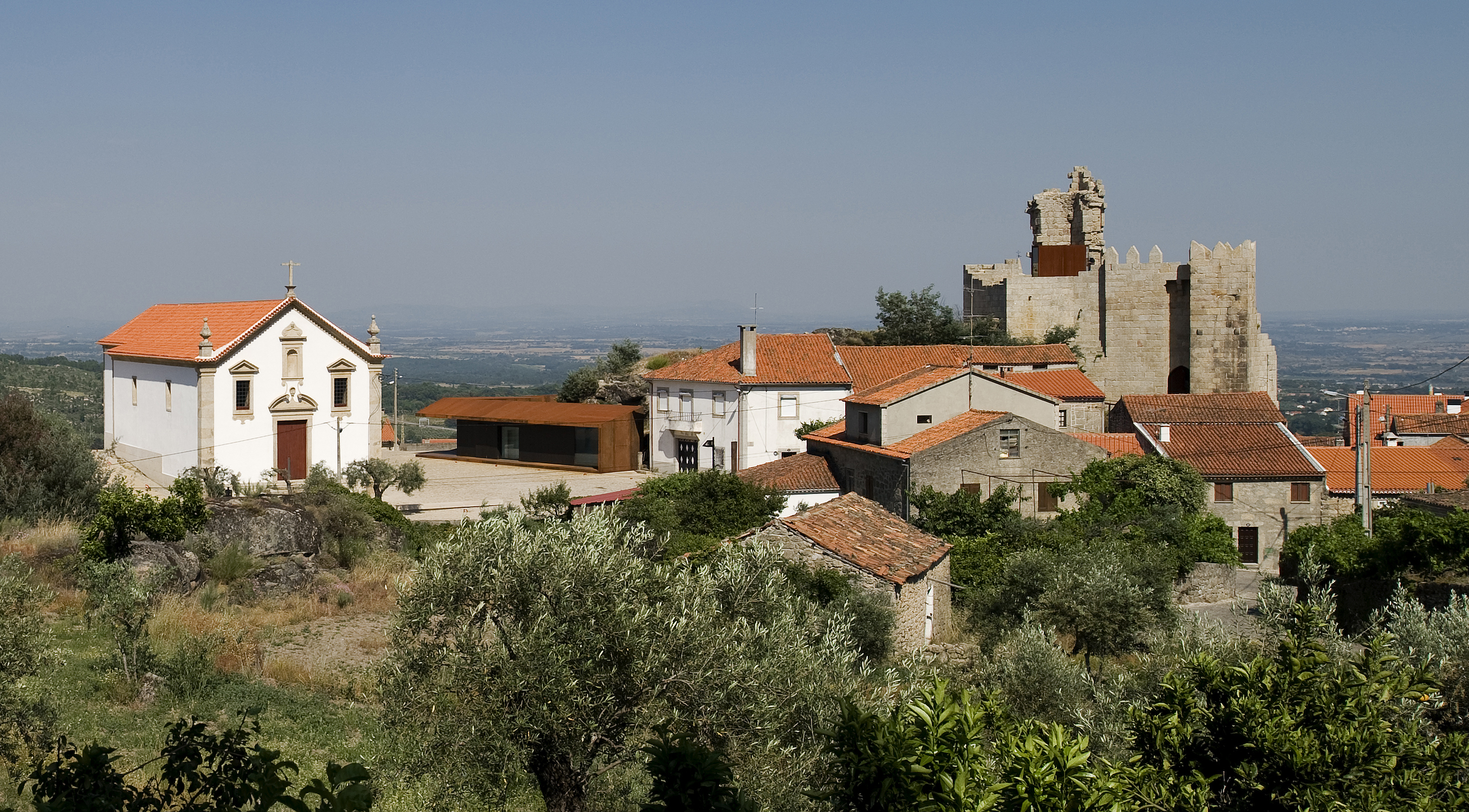 The long, low volume of the visitor pavilion addresses an existing church and square